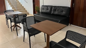 A lobby with a staircase, a sofa, and a table with chairs. - Mais Hotel (Araguaina)