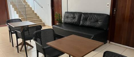 A lobby with a staircase, a sofa, and a table with chairs.
