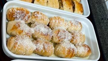 Três bandejas com produtos de panificação, provavelmente doces, em um ambiente de cozinha.