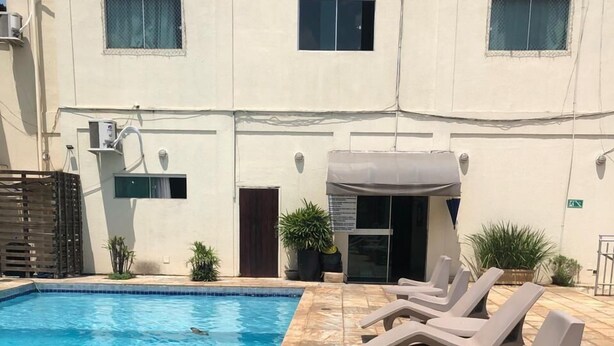 A swimming pool with lounge chairs and potted plants. - Mais Hotel (Araguaina)