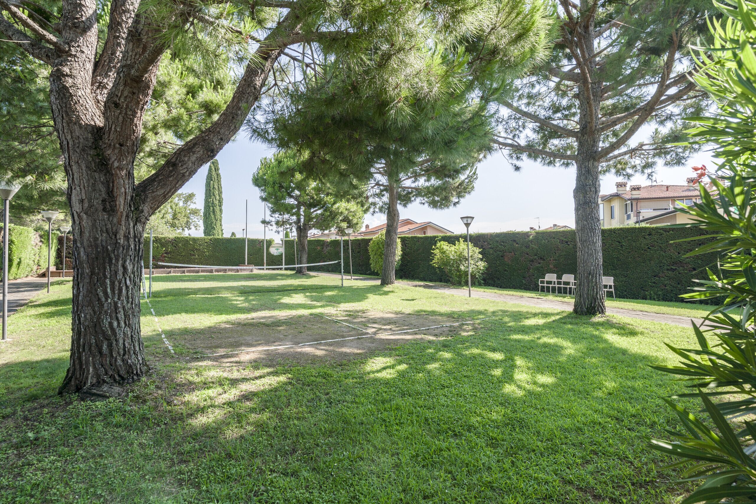 Un court de tennis entouré d’arbres et d’une haie.