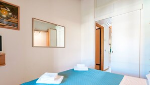 A hotel room with a bed, a mirror, and a painting on the wall.