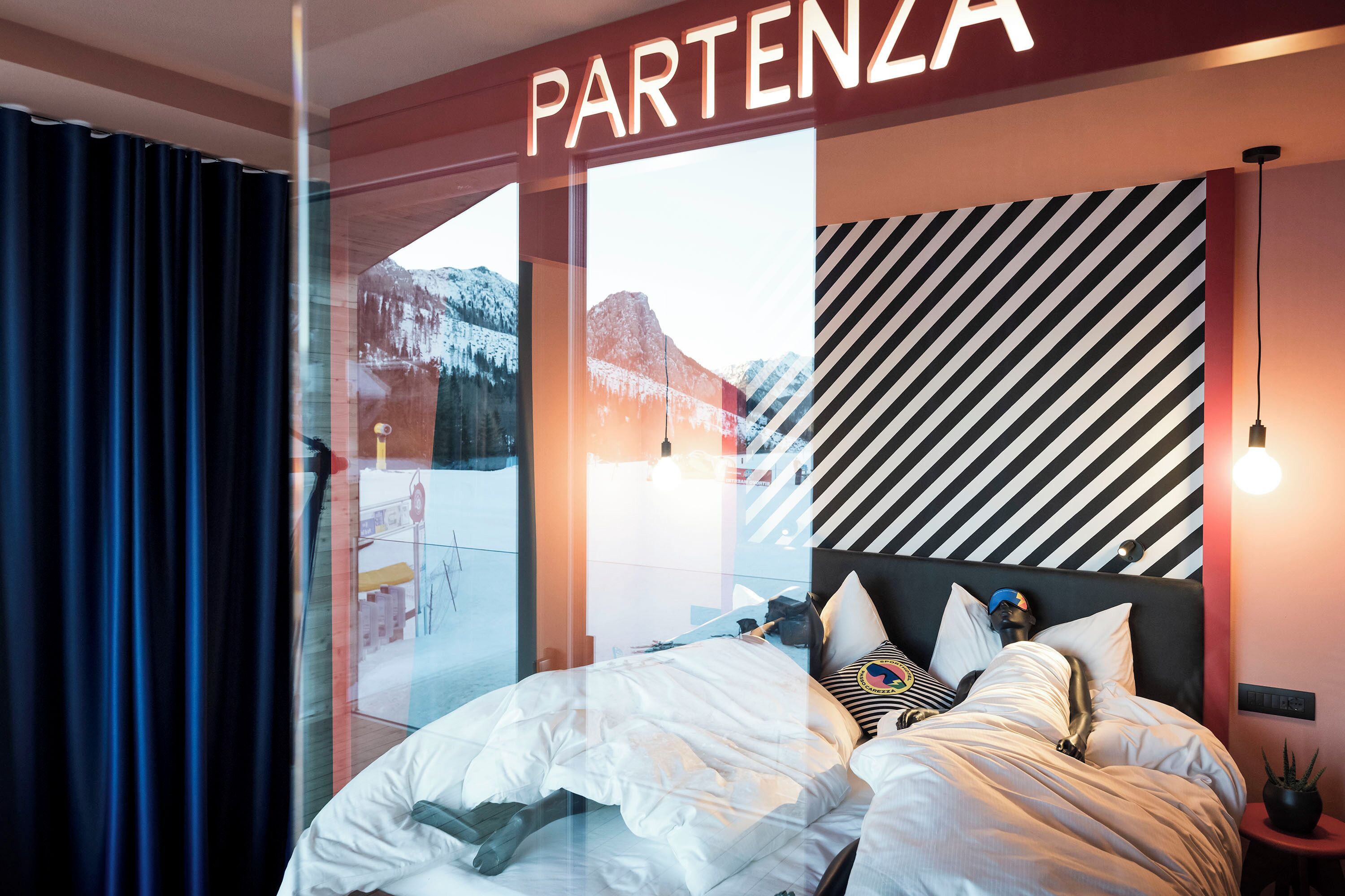 Ein Hotelzimmer mit Bett und Blick auf Berge, mit einem Schild, auf dem 'PARTENZA' steht.