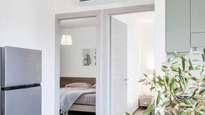 A modern bedroom with a bed, bedside table, and a hanging lamp.