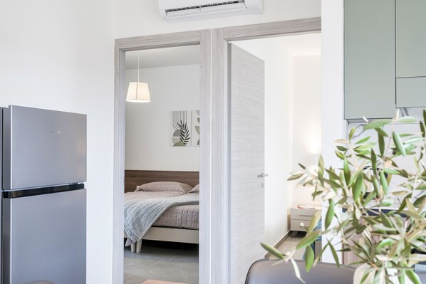 A modern bedroom with a bed, bedside table, and a hanging lamp.