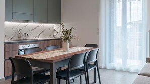 A modern kitchen with a marble countertop, wooden cabinets, and a dining area with a table and chairs.