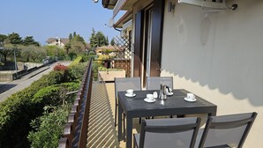 A balcony with a table set for two, chairs, and a coffee pot.