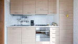 A modern kitchen with light wood cabinets, stainless steel appliances, and a tiled backsplash. - Regarda - La Terrazza di Garda lake view apartment with terrace (Garda)