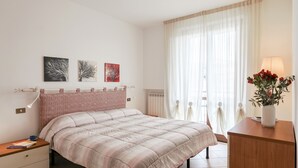 A bedroom with a bed, bedside table, lamp, and artwork on the wall.