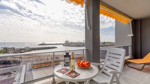 A balcony with a table, chairs, and a view of the sea.