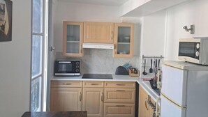 Eine kleine Küche mit Holzausstattung, einer Mikrowelle, einem Toaster und einem Kühlschrank.