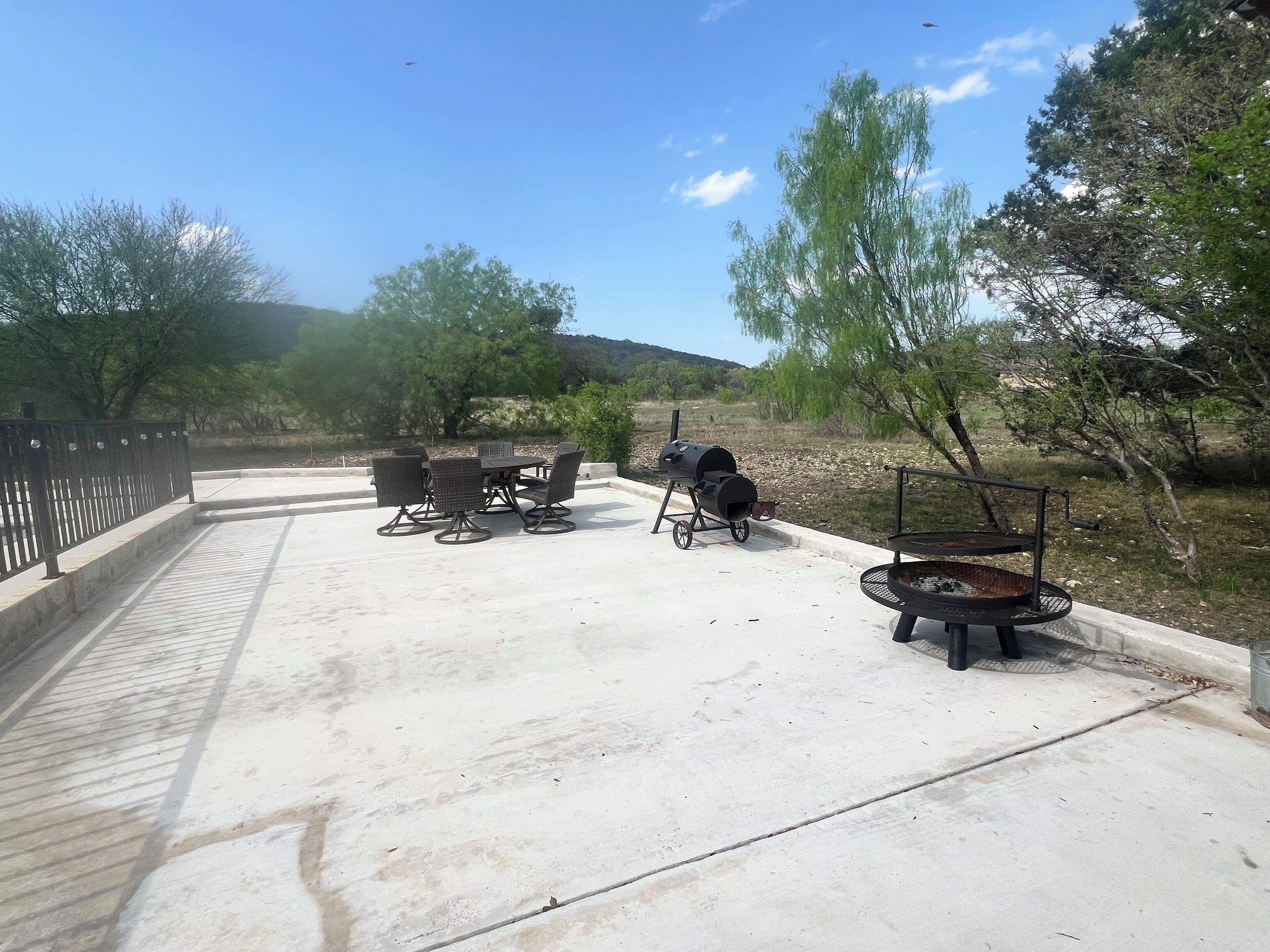 Eine Terrasse im Freien mit Grill, Tisch mit Stühlen und einem Feuerkorb.