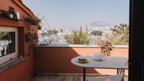 A balcony with a table set for tea, potted plants, and a view of the cityscape. - La Rocca Sulla Cala by Wonderful Italy (Palermo)