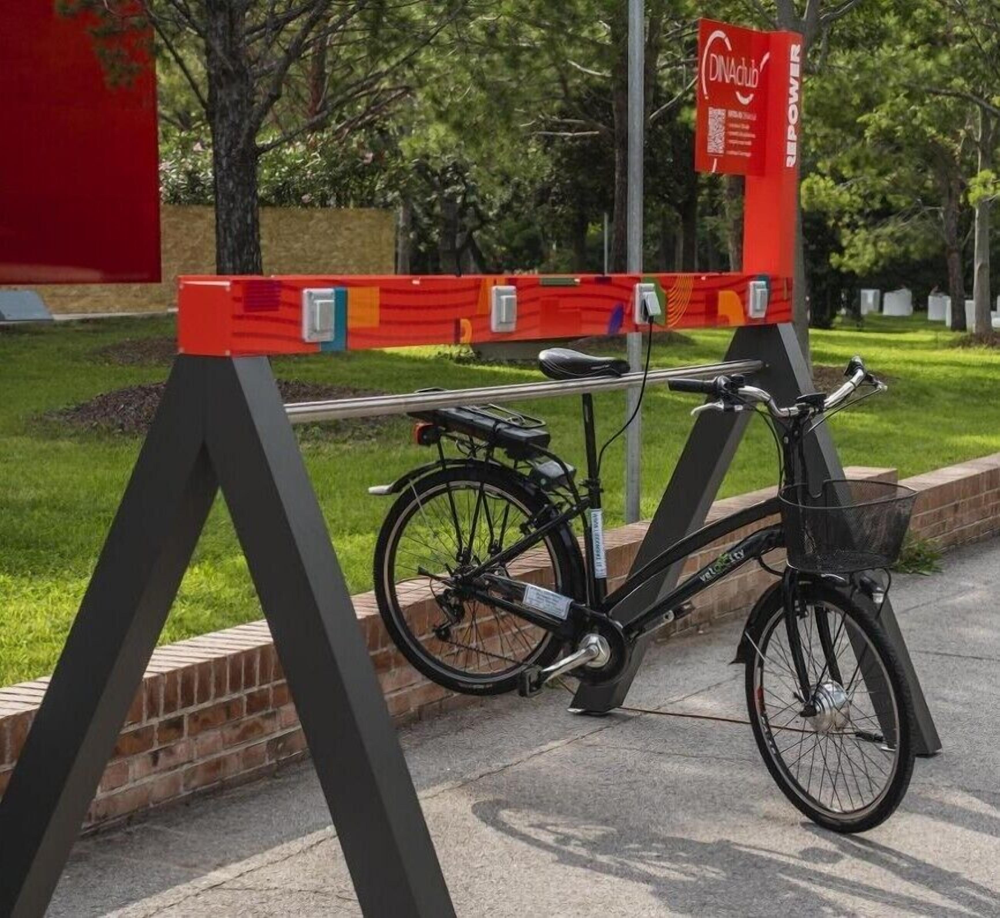 Un vélo d’appartement est garé à côté d’une barrière rouge sur laquelle est apposé un panneau « DNAbio ».