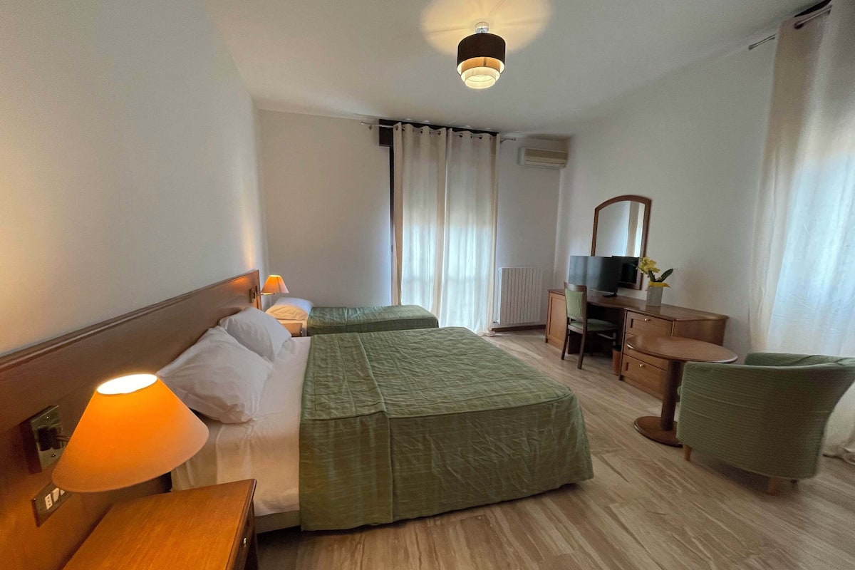 A hotel room with two beds, a desk with a chair, a television, and a mirror.