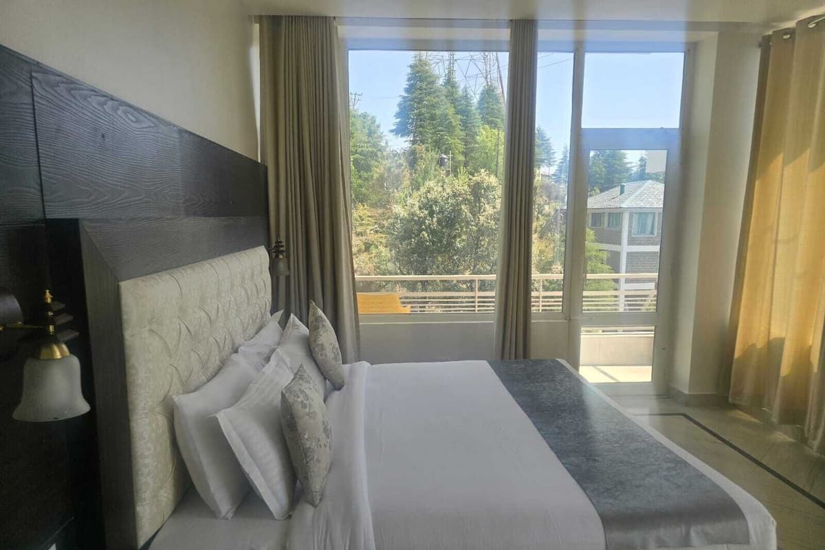 Quarto com uma cama grande, cabeceira e vista para o exterior através de uma varanda.