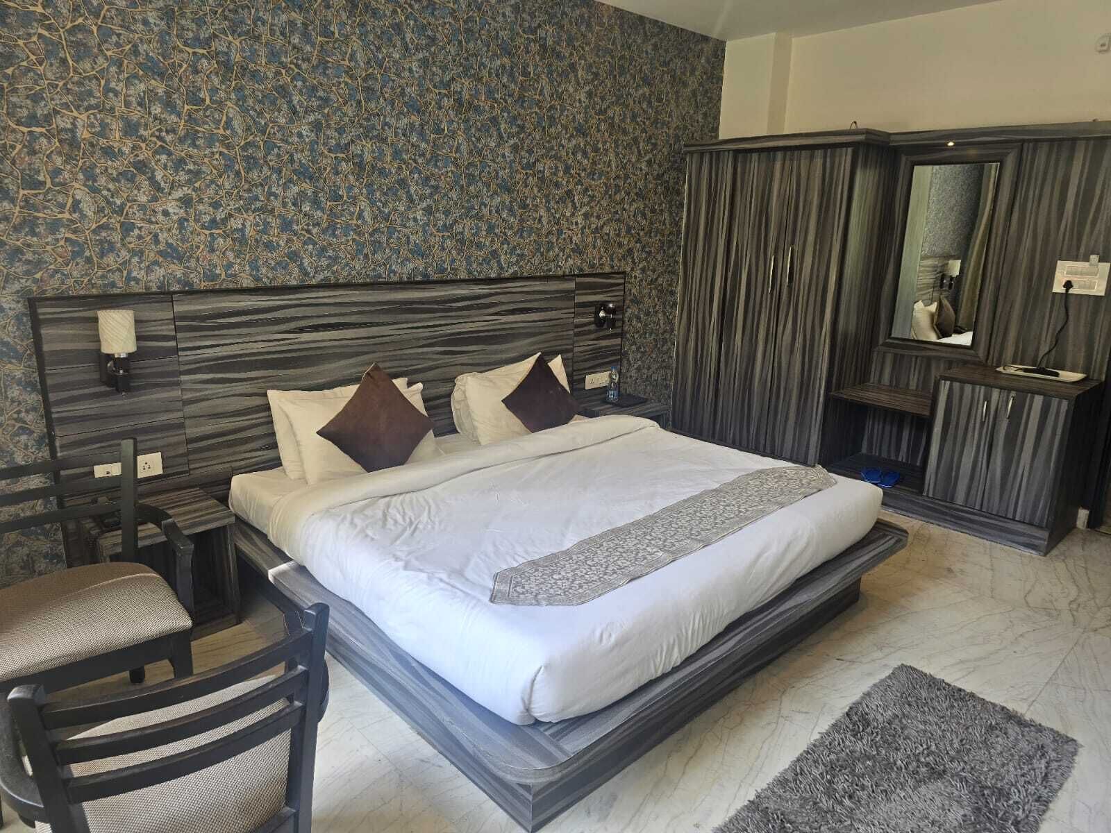 A modern bedroom with a large bed, a nightstand, a chair, and a wardrobe.