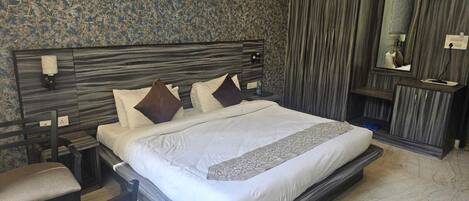 A modern bedroom with a large bed, a nightstand, a chair, and a wardrobe.