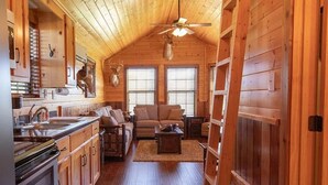 A log cabin interior with a kitchen, dining area, and living room. - Secluded Cabin in Weatherford, TX (Weatherford)