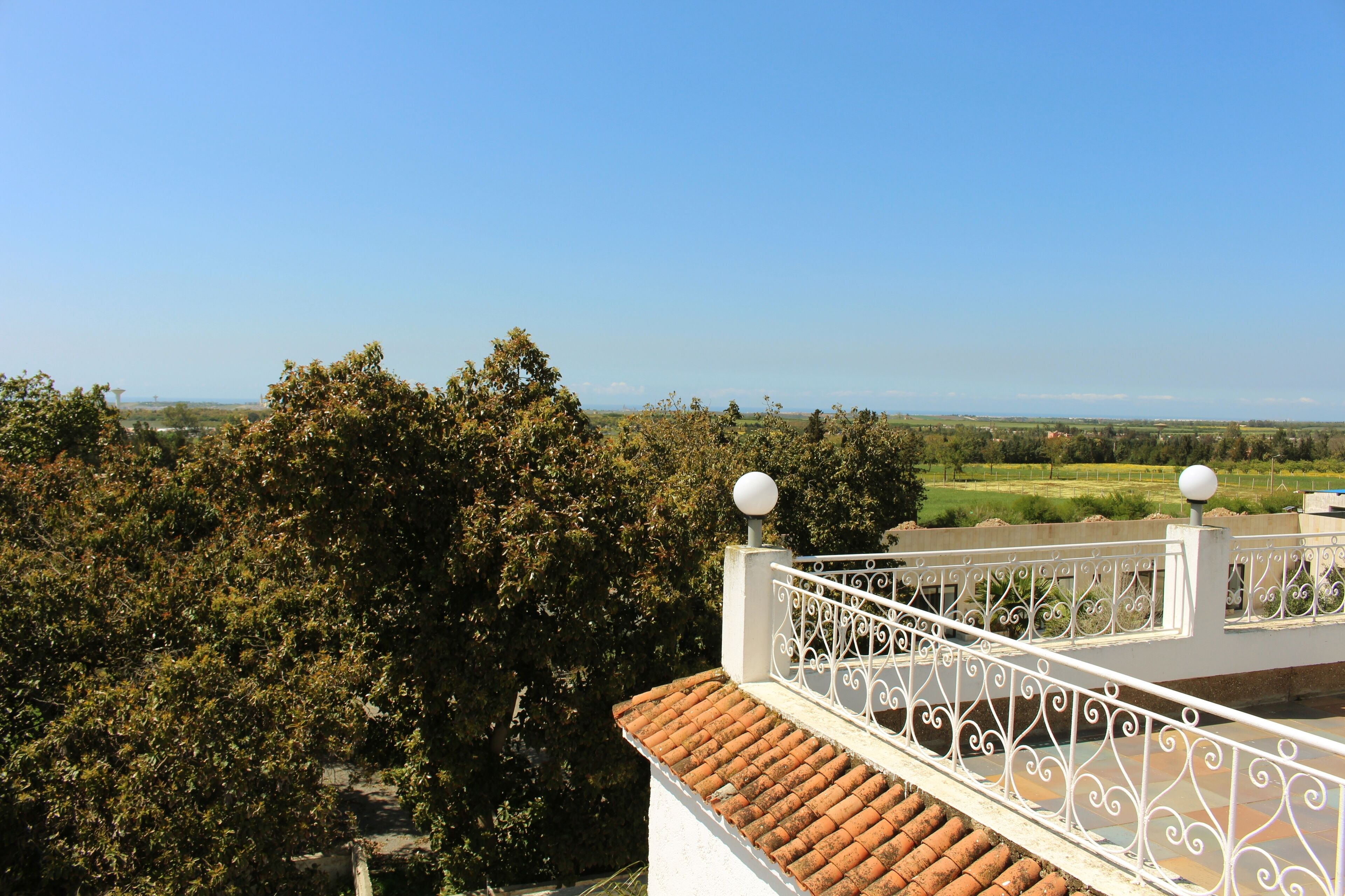 Une terrasse sur le toit, dotée d’une balustrade blanche et offrant une vue sur un paysage verdoyant.