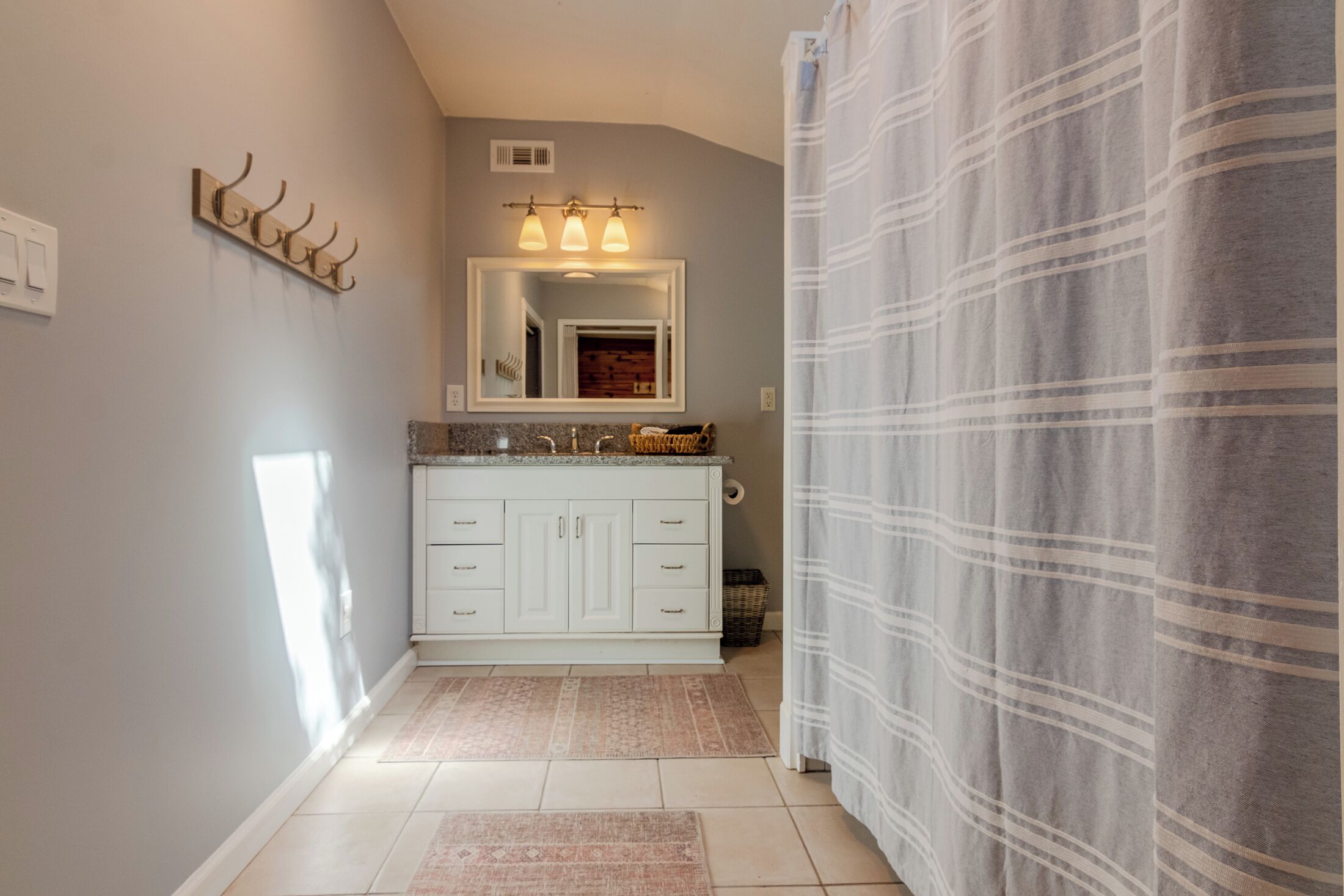 Une salle de bain avec un meuble-lavabo blanc, un miroir et un porte-serviettes.