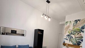 A modern bedroom with a blue sofa, a bed with a white headboard, a black wardrobe, and a wall-mounted mirror. - Studio Centre Paris  Opera (Paris)