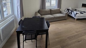 A modern, well-lit room with a dining table, sofa, and bed. - Studio Grands Boulevards (Paris)