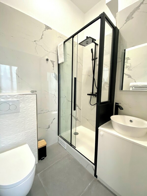 Une salle de bain moderne avec une douche à parois de verre, un lavabo blanc et des toilettes.