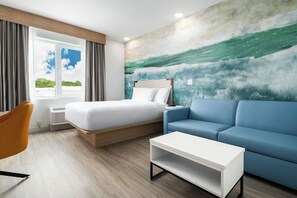 A modern hotel room with a bed, sofa, and a painting on the wall. - YourSpace Hotels Chesapeake (Chesapeake)