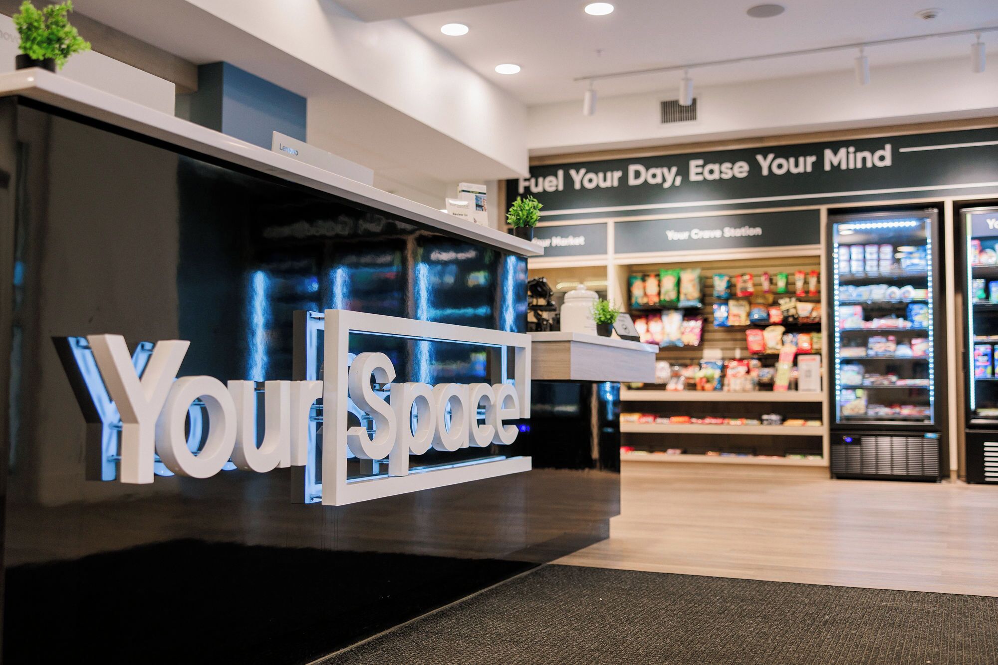 A reception desk with a sign reading 'Your Space' and a wall with a sign that says 'Fuel Your Day, Ease Your Mind.'
