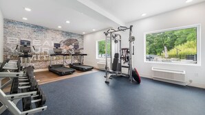 A gym with treadmills, weight machines, and a brick wall. - YourSpace Hotels Chesapeake (Chesapeake)