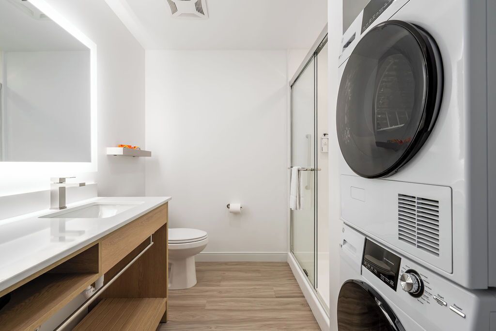 Un baño moderno con lavamanos, inodoro y lavadora integrada.