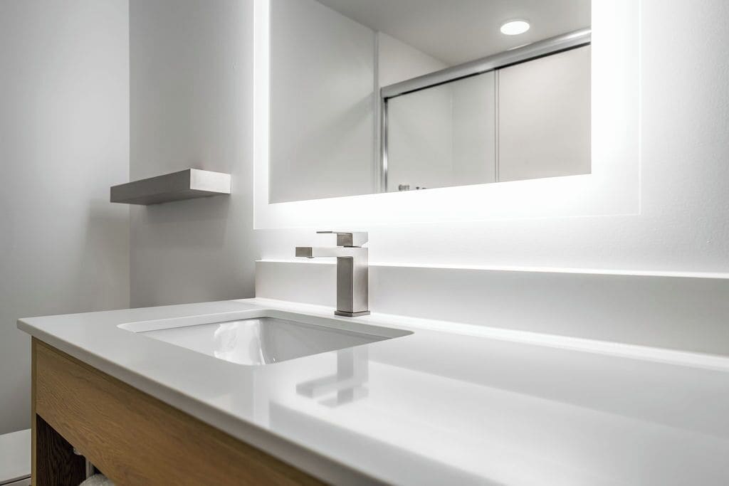 Une salle de bain moderne avec un lavabo blanc, un miroir et un meuble en bois.
