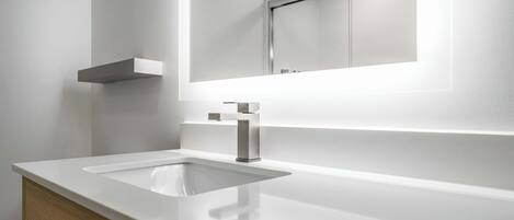 Une salle de bain moderne avec un lavabo blanc, un miroir et un meuble en bois.