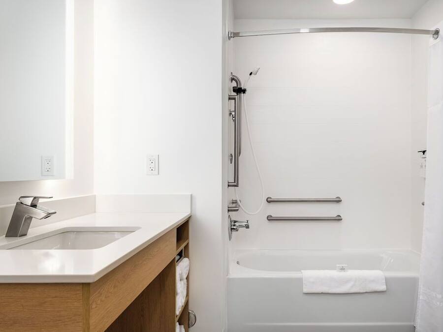 A modern bathroom with a sink, mirror, shower, and bathtub.