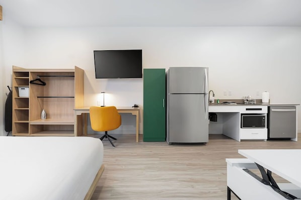 A hotel room with a bed, a desk, a chair, a TV, a refrigerator, a microwave, and a small kitchenette. - YourSpace Hotels Chesapeake (Chesapeake)