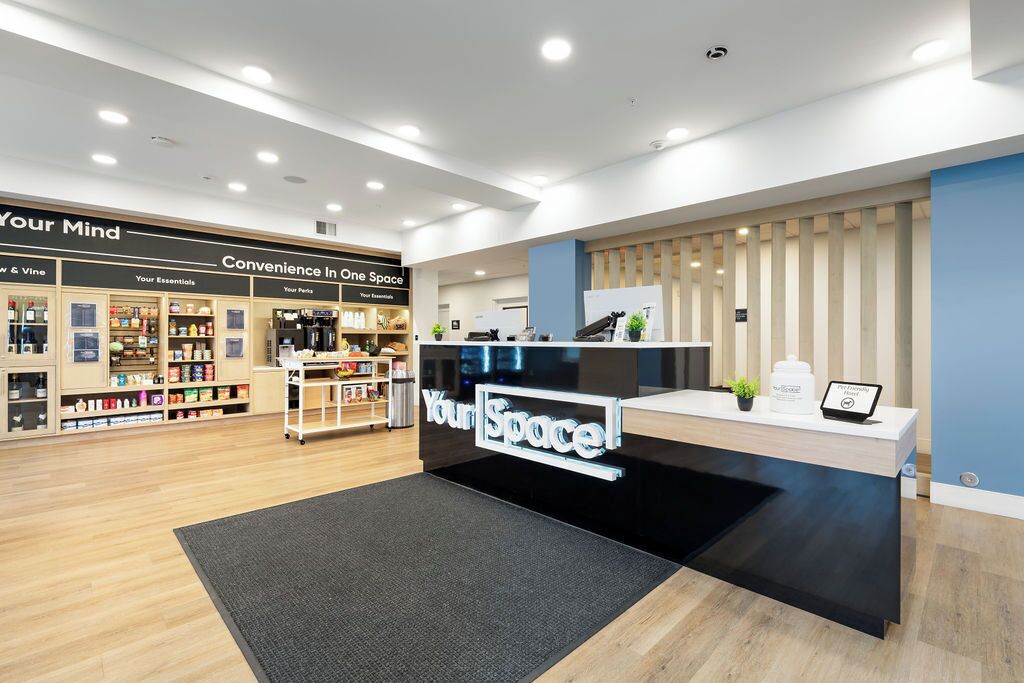 Zona de recepción con mostrador, un cartel que dice 'Your Space' y estantes con productos.