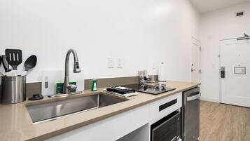 A modern kitchen with a stainless steel sink, a dishwasher, and a countertop with kitchen utensils.