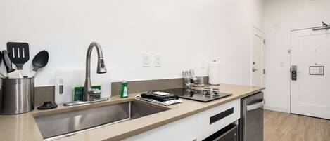 Une cuisine moderne dotée d’un évier en acier inoxydable, d’un lave-vaisselle et d’un plan de travail agrémenté d’ustensiles de cuisine.