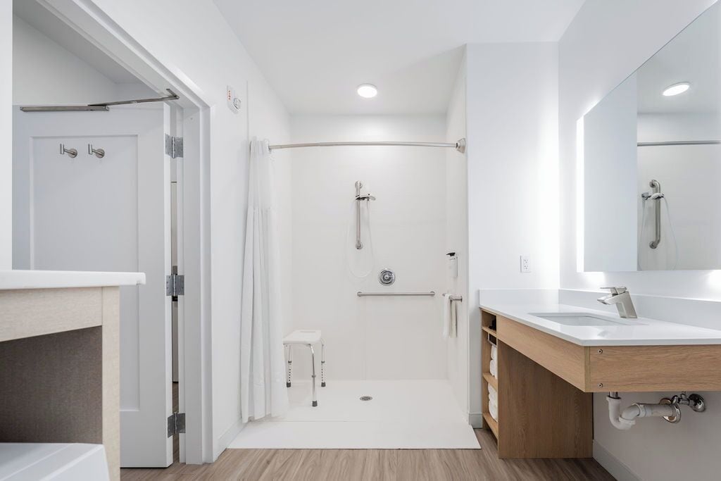 Un baño moderno con ducha, lavamanos y espejo.