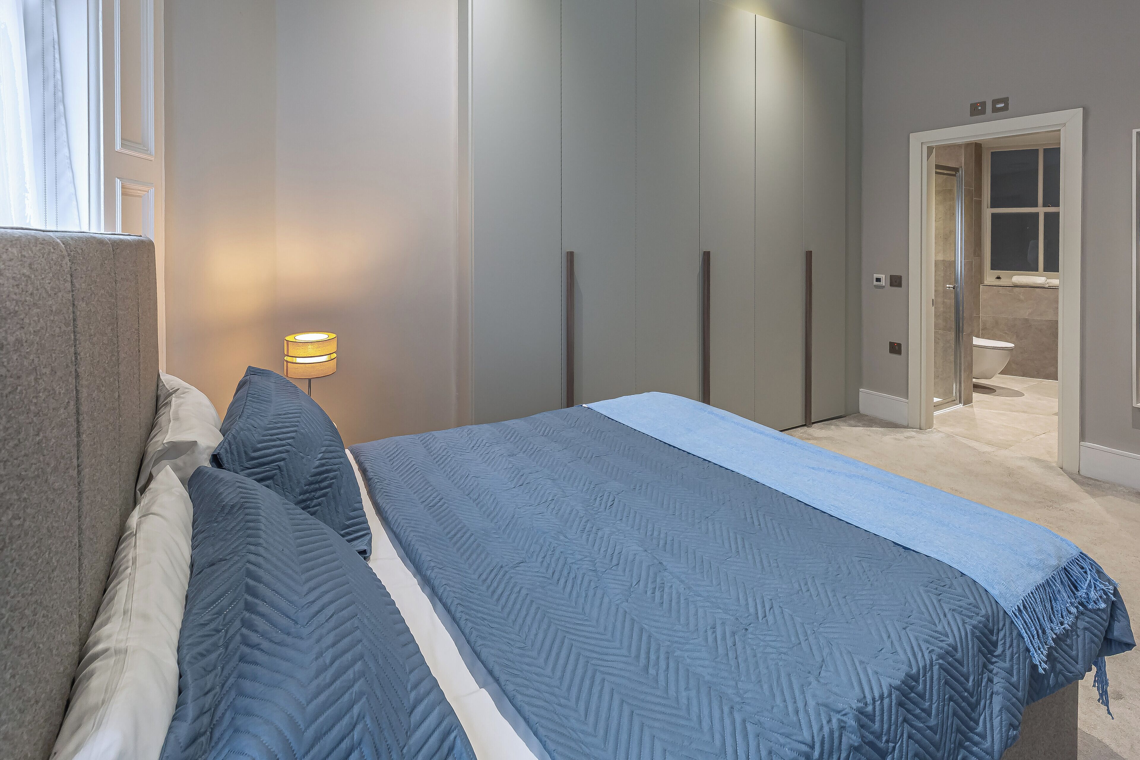 Une chambre à coucher avec un lit, une table de chevet et une lampe fixée au mur.