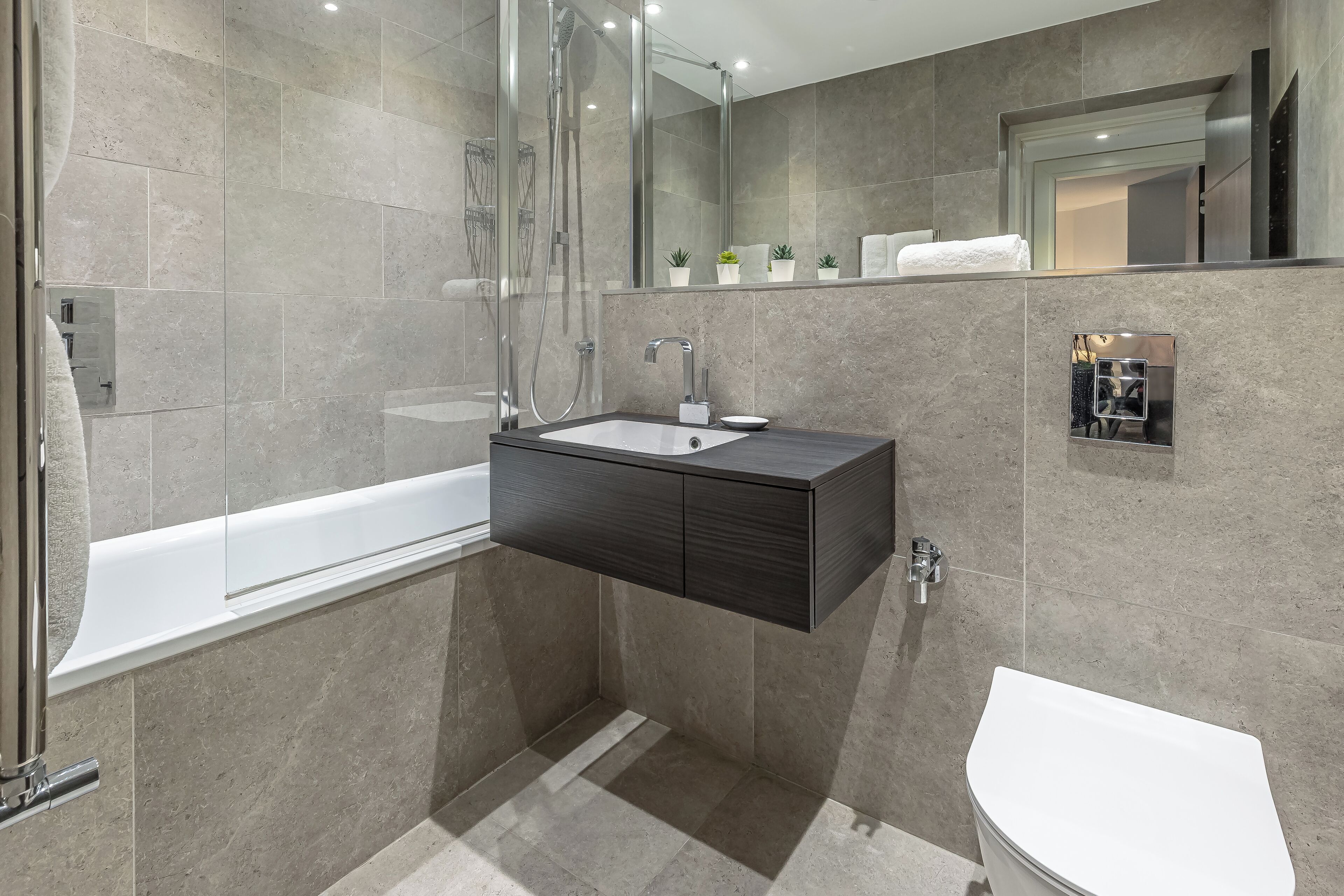 Un baño moderno con una bañera independiente, un tocador con lavabo y un inodoro.