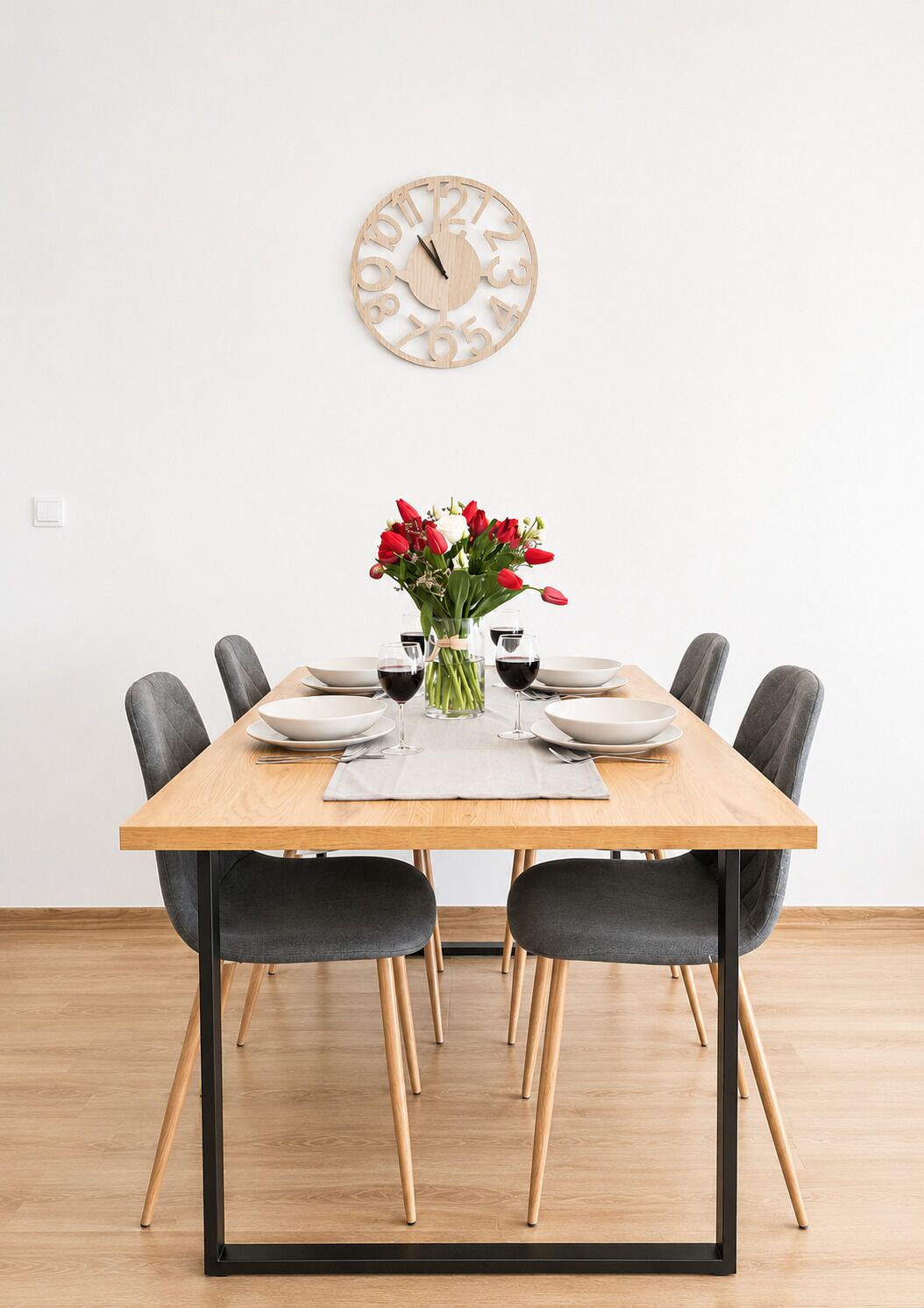 Ein Esstisch mit sechs Stühlen, eine Blumenvase und eine Wanduhr.