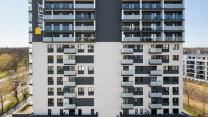 A modern apartment building with a flat facade, multiple balconies, and a parking area with marked spaces. - Lumina stylish apart near Pasaż Łódzki (Lódz)