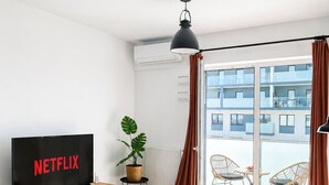 A modern living room with a TV, a laptop, a coffee table, a sofa, and a balcony with chairs. - Lumina stylish apart near Pasaż Łódzki (Lódz)