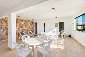 A spacious indoor area with a stone wall, a round table with chairs, and a sign indicating a sauna.