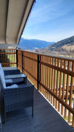 A balcony with wicker furniture and a view of a mountainous landscape. - Bergzauber Appartements (Rennweg am Katschberg)