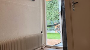 Une pièce avec un radiateur, une porte portant l’inscription « WC », et un tableau coloré accroché au mur.