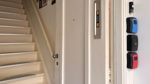 Un escalier menant à une porte blanche dotée d’un judas et d’un interphone fixé au mur.