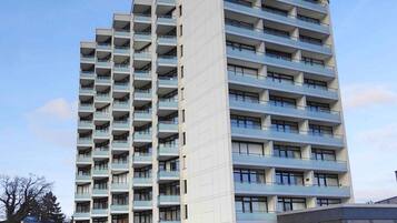 Ein Hochhaus mit mehreren Balkonen, einem Swimmingpool und blauem Himmel.